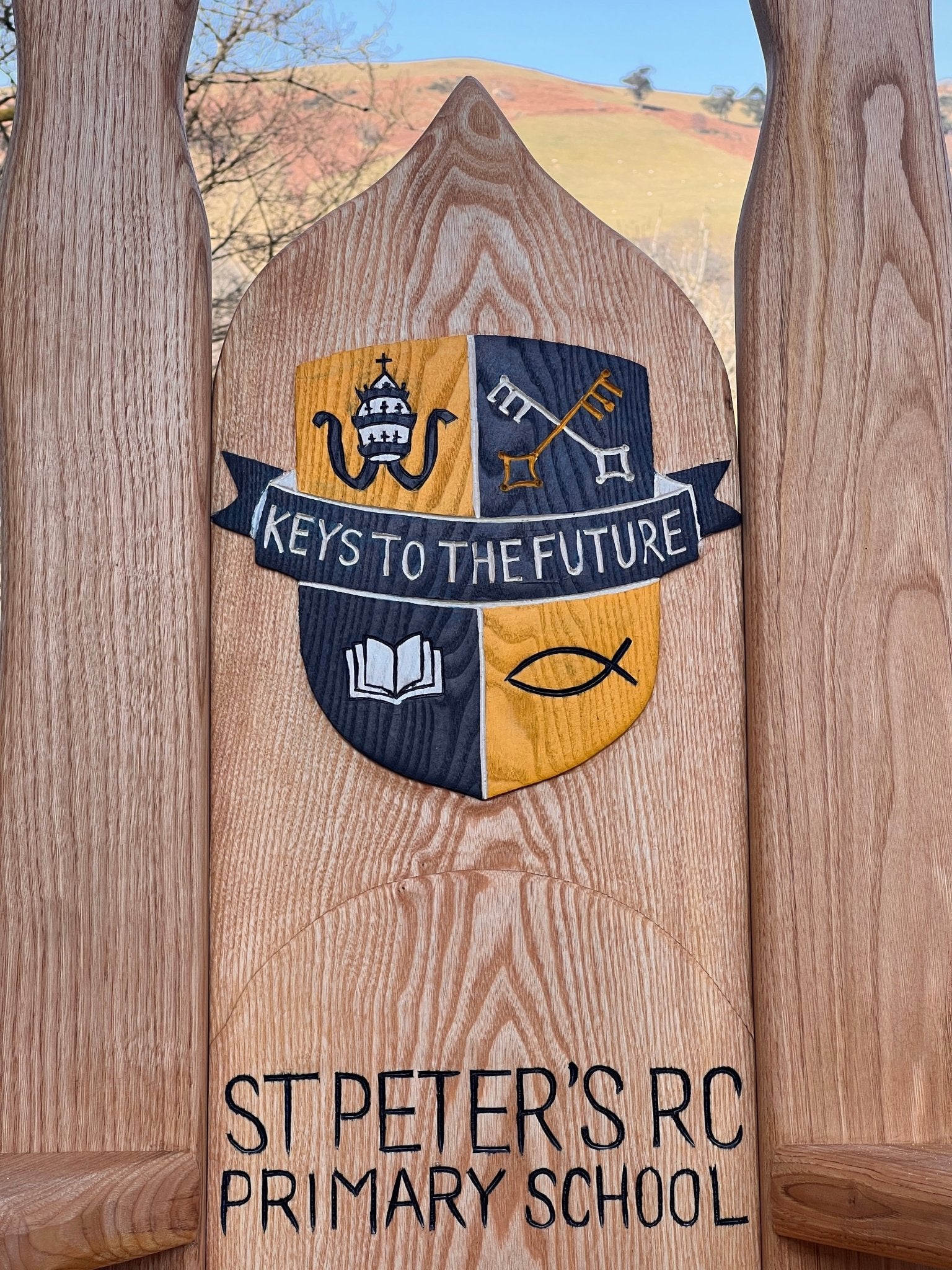 Custom oak storytelling chair featuring school logo and lettering, designed for outdoor learning spaces