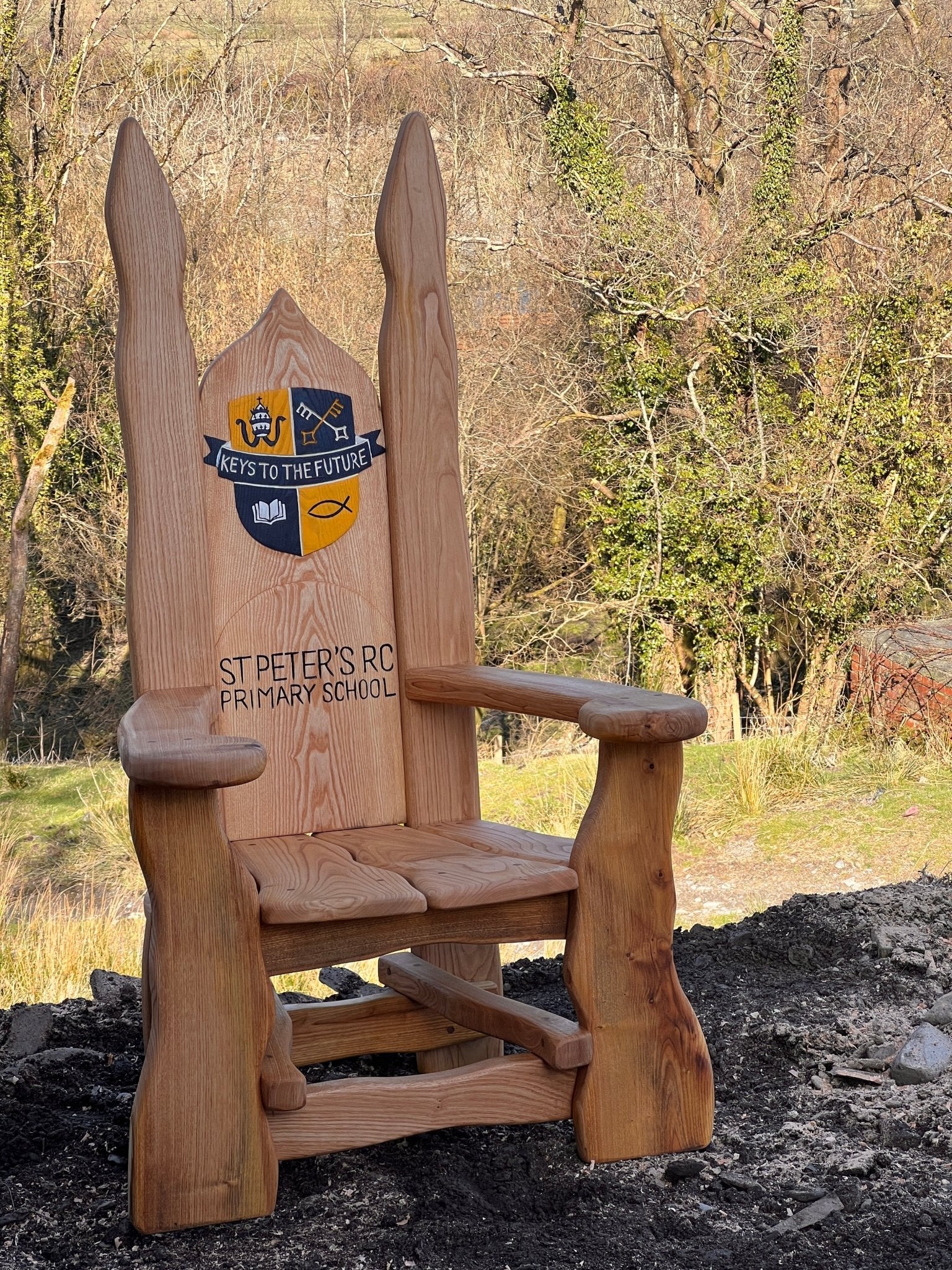 Custom oak storytelling chair featuring school logo and lettering, designed for outdoor learning spaces