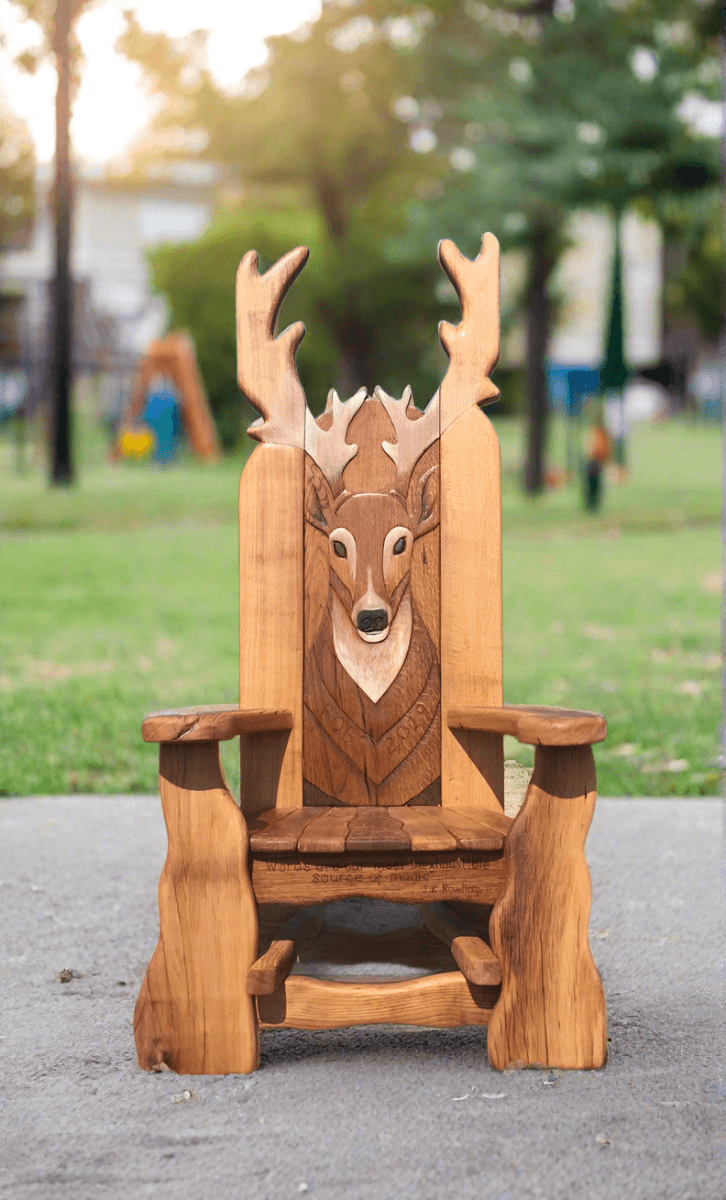 Handmade solid oak stag storytelling chair in park setting — carved woodland reading throne, Wales