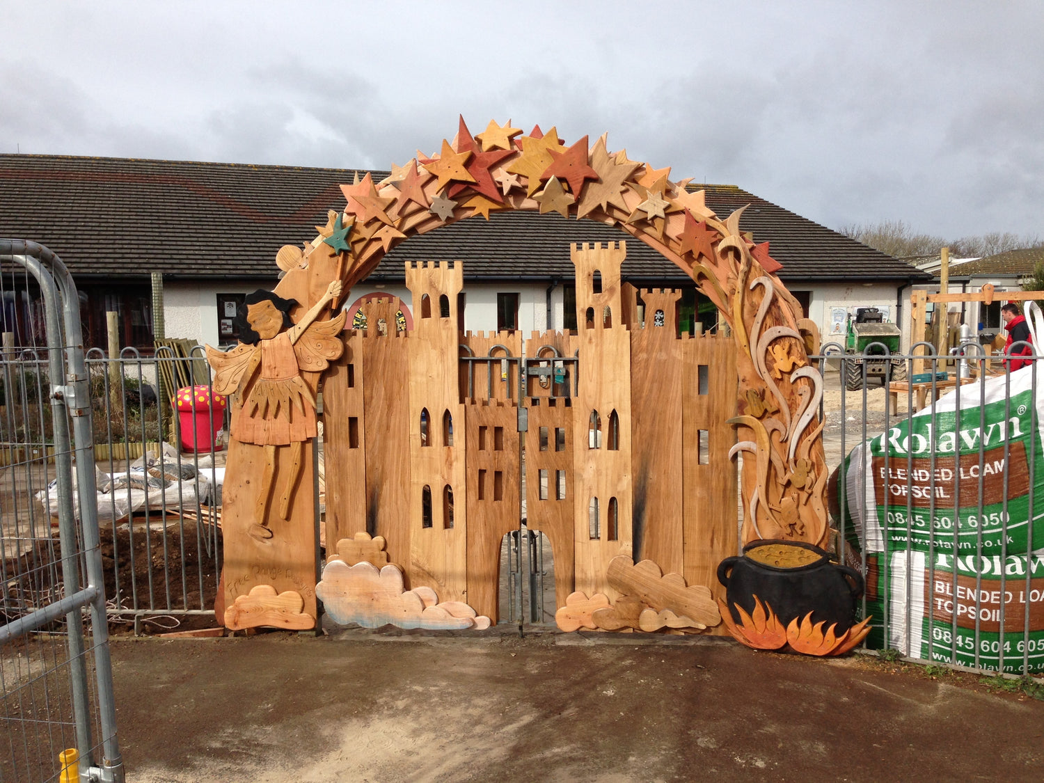 Wooden archway with castle design and Halloween decorations in front of a building.