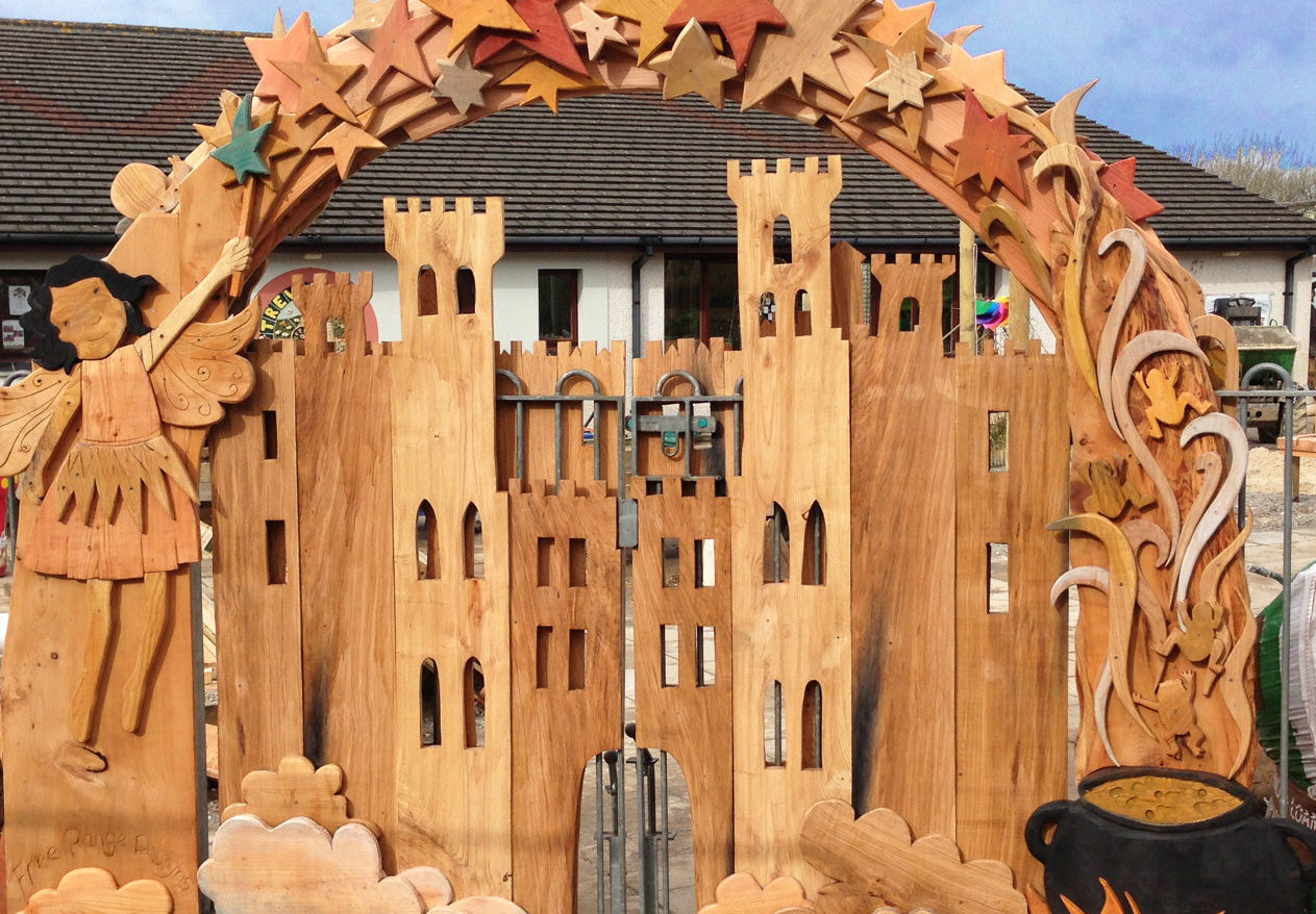 Wooden fairy tale castle with decorative archway featuring stars and a fairy figure.