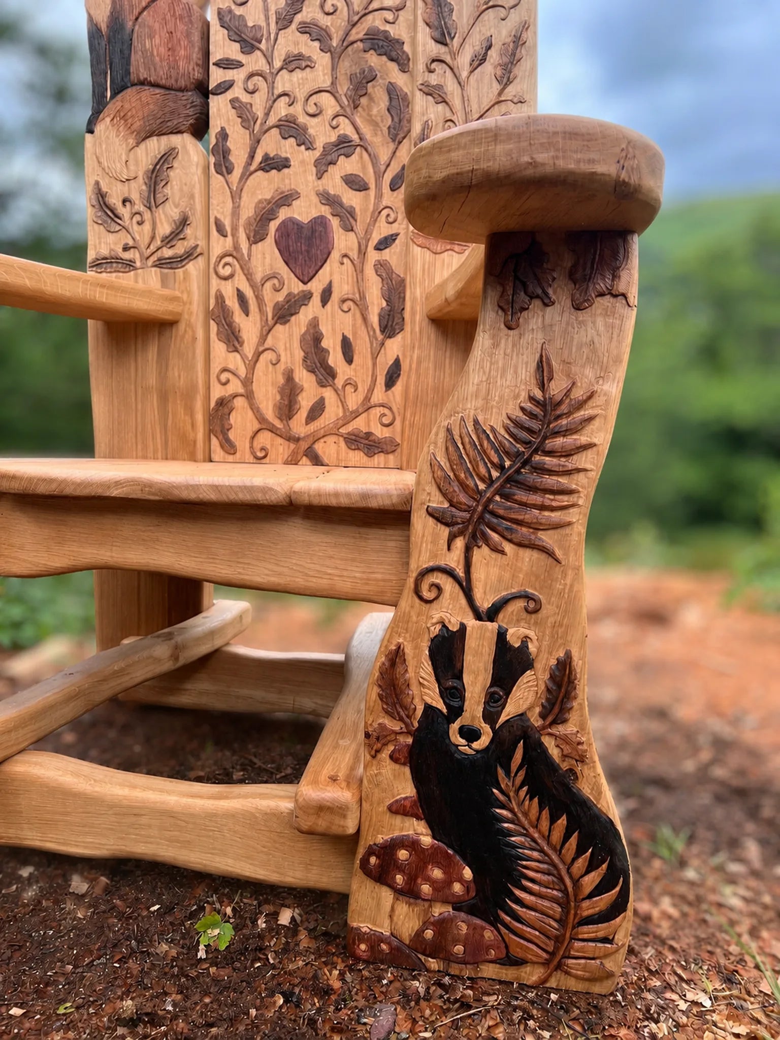 Hand-carved badger with fern and toadstools on the oak arm of a woodland storytelling school chair