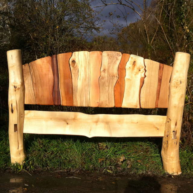 Close-up of driftwood headboard on handmade stripy bed — sustainable colourful bedroom furniture, Wales