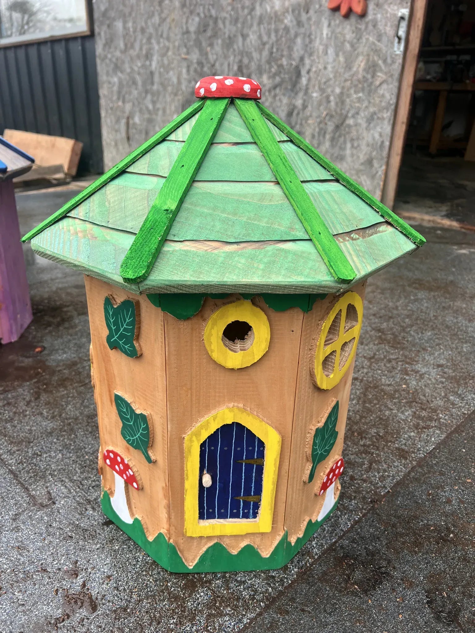Side view of tree fairy house tower showing natural branch columns and hand-painted cottage details