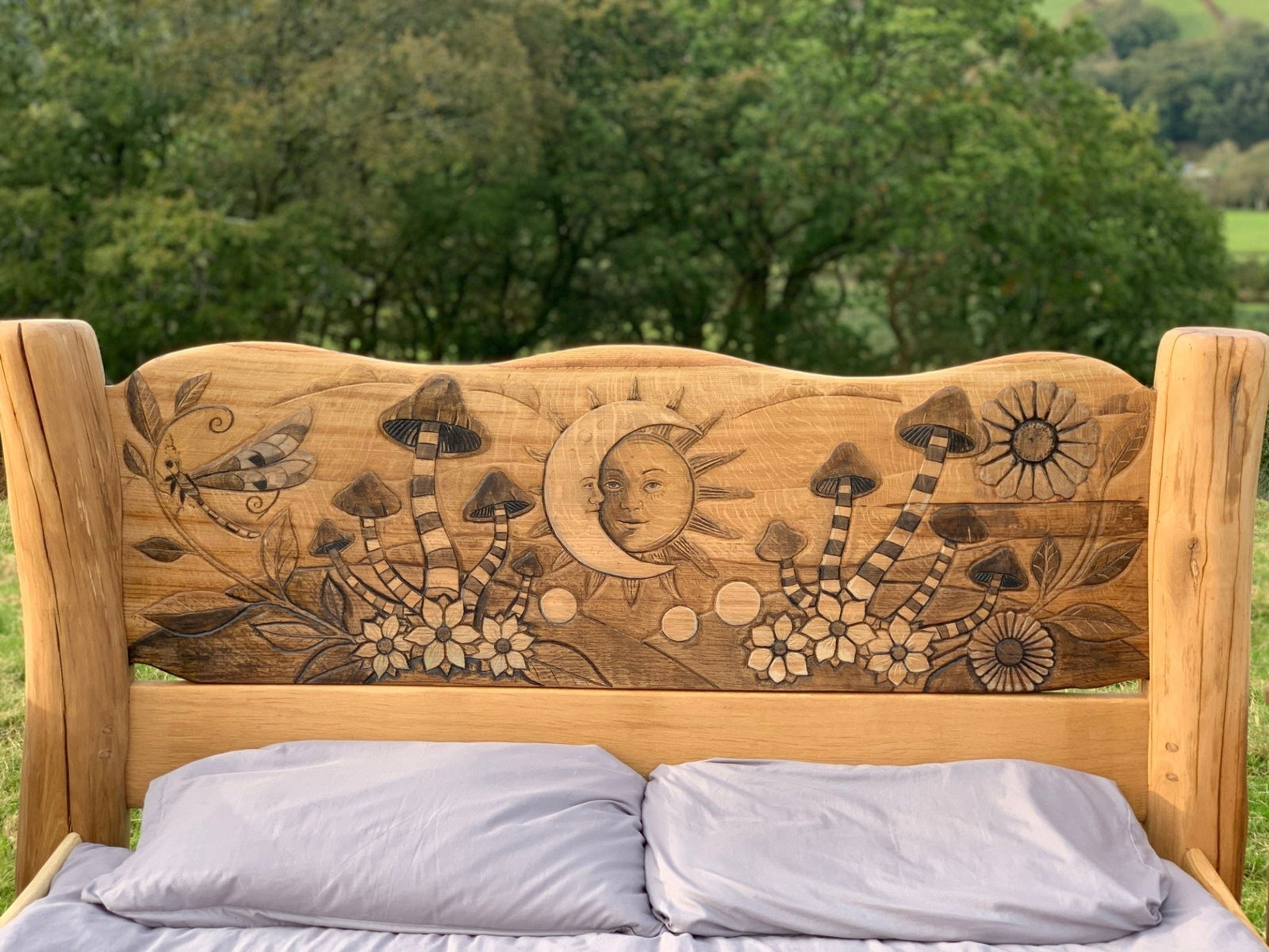 Headboard with sun and mushroom carvings on bespoke solid oak bed — handmade in Wales