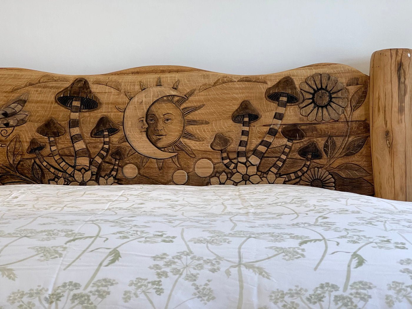 Headboard carvings of mushrooms and sun on bespoke solid oak fantasy bed — handmade in Wales