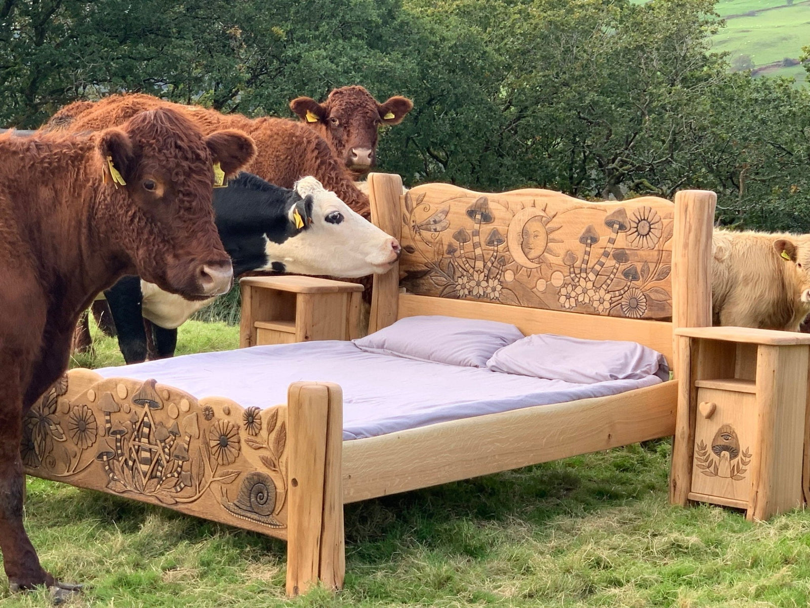 Bespoke solid oak fantasy bed with carved designs surrounded by cows — handmade in Wales