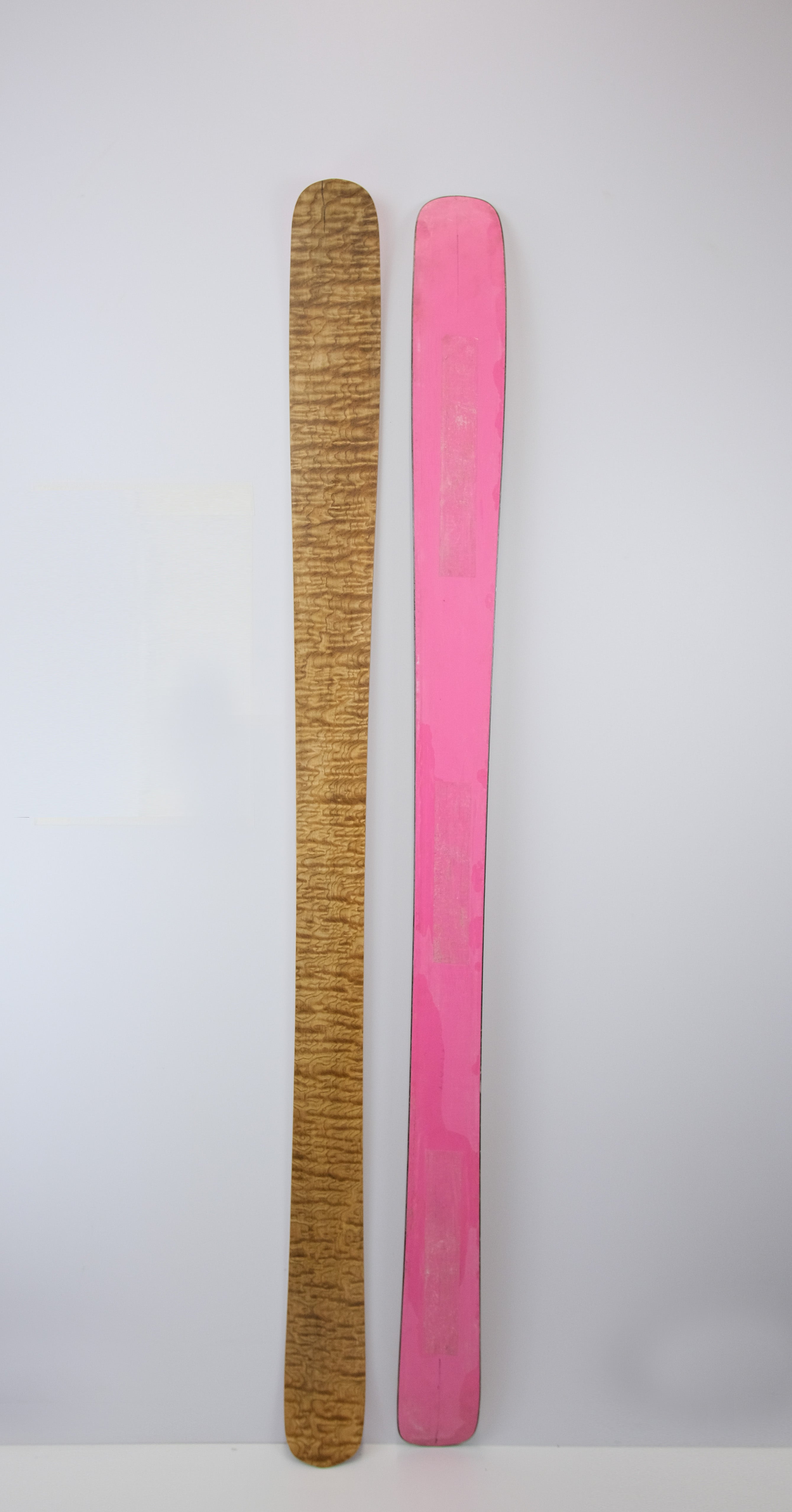 Side-by-side display of the Twin Tip 98 skis, with one ski showing the ash topsheet and the other showing the vibrant pink base.