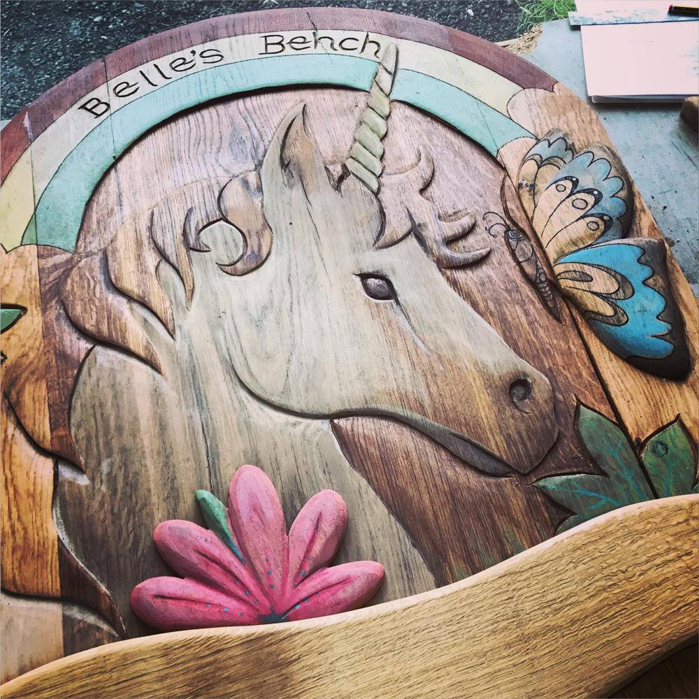 Close-up of carved unicorn on handmade oak memorial bench — bespoke tribute seating, Wales