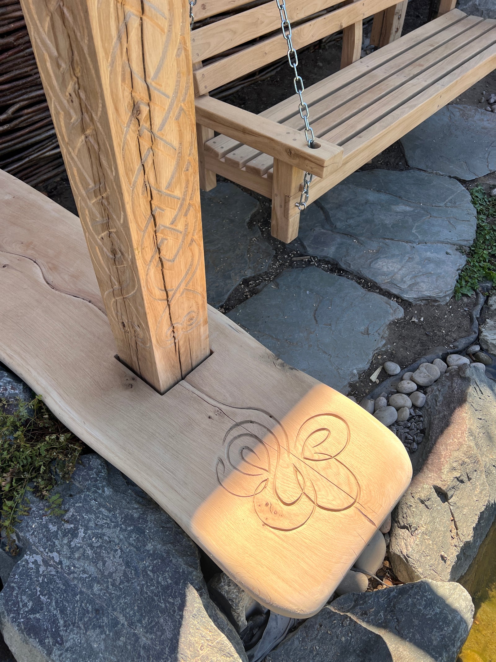 Live-edge oak base slab with hand-carved Celtic motif at the foot of the Viking garden arbour