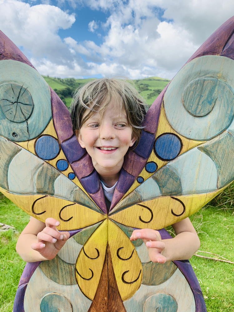 Child peeking through butterfly wings of fairy chair