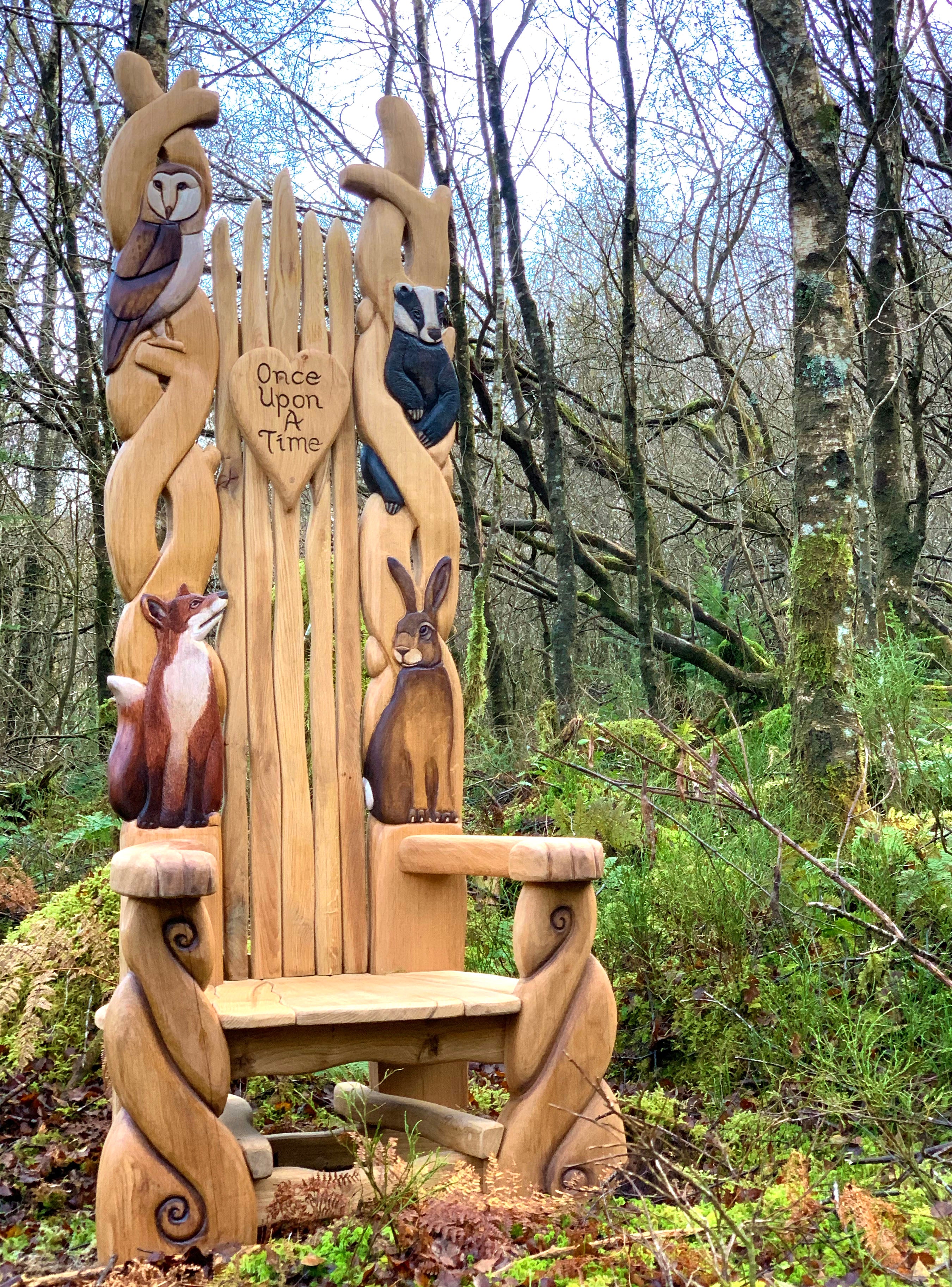 Chaise en bois avec des sculptures d'animaux dans une zone boisée.