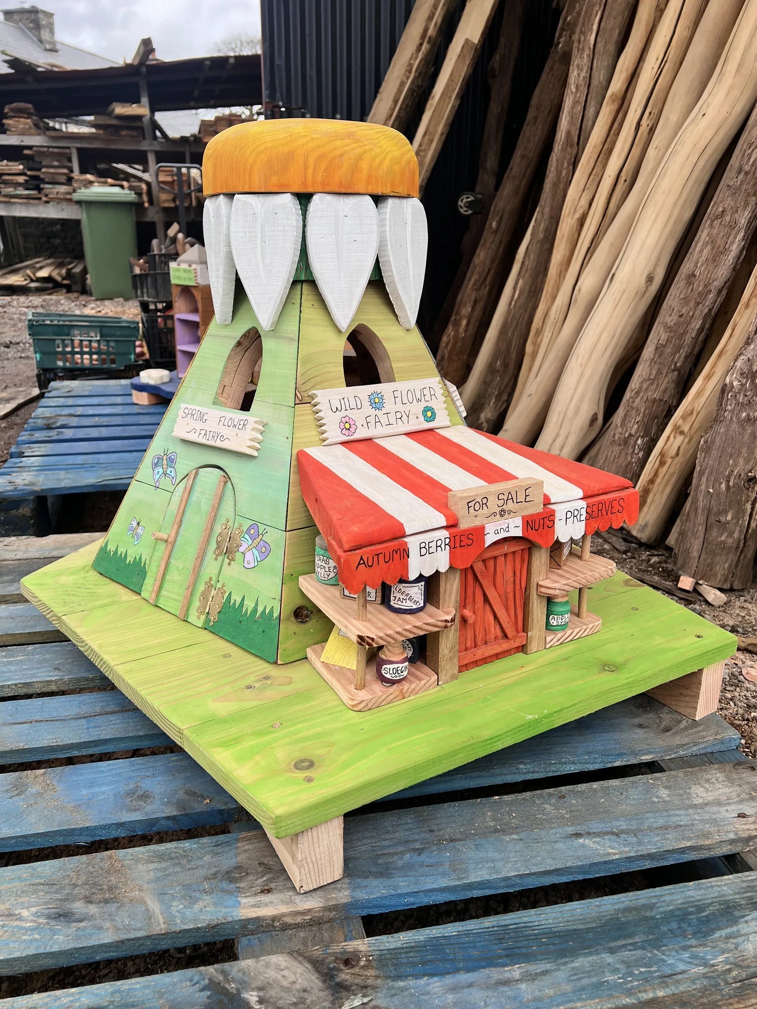 Side view of wildflower fairy house showing botanical paintwork and reclaimed timber construction