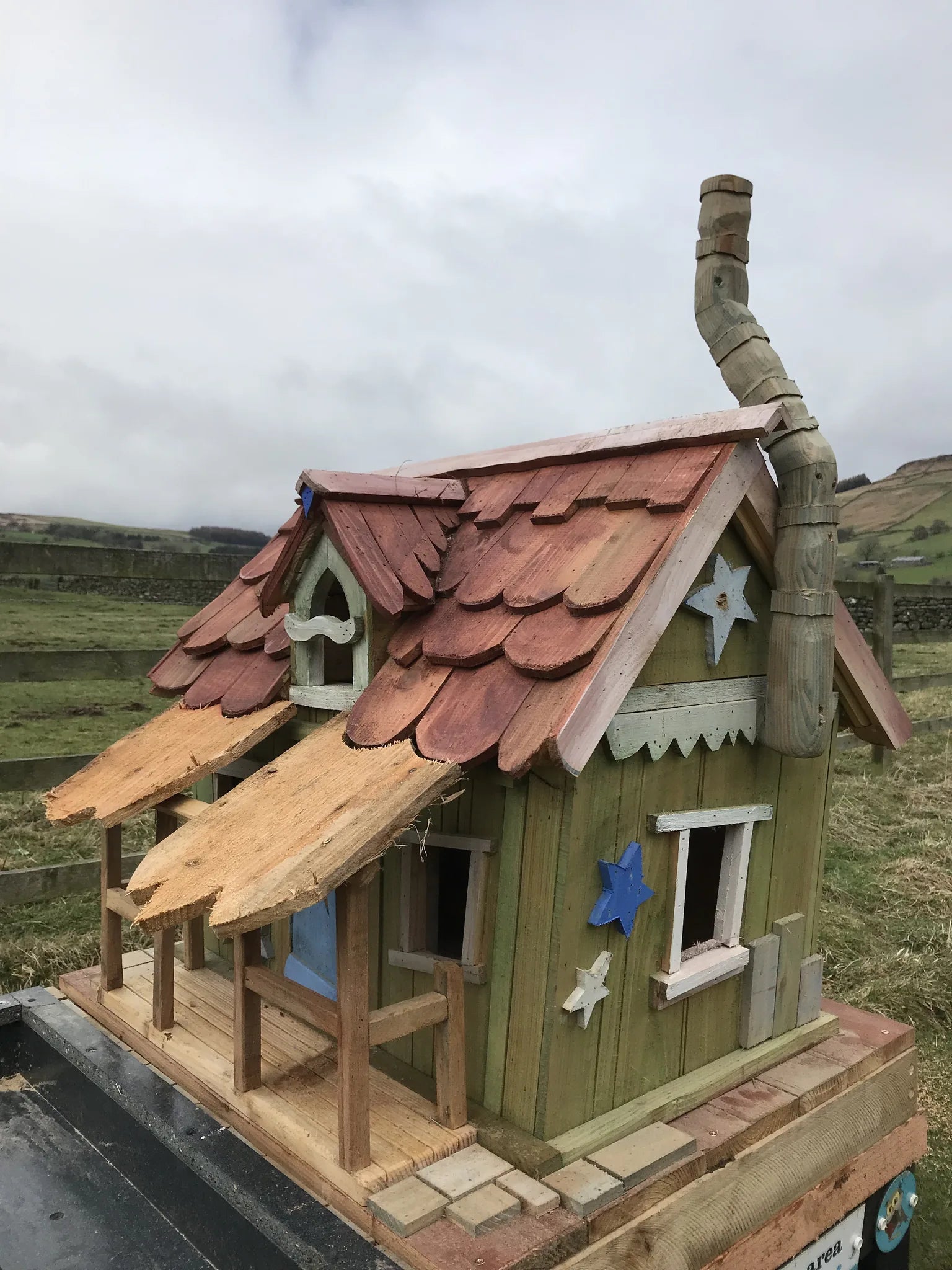 Close-up of fairy wishing cottage well with hand-carved wooden bucket and decorated wooden surround