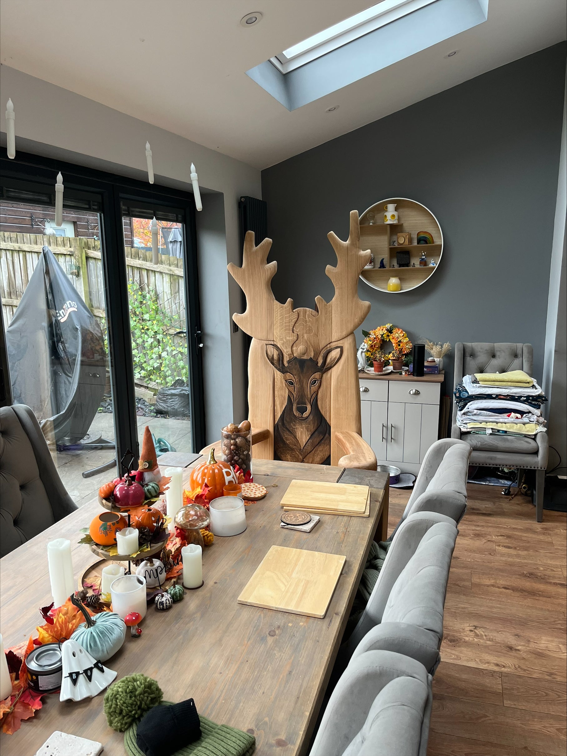 Hand-carved wooden stag chair with detailed antlers and a lifelike deer face, placed at the head of a dining table. This unique and bespoke piece adds a majestic touch to the dining room.