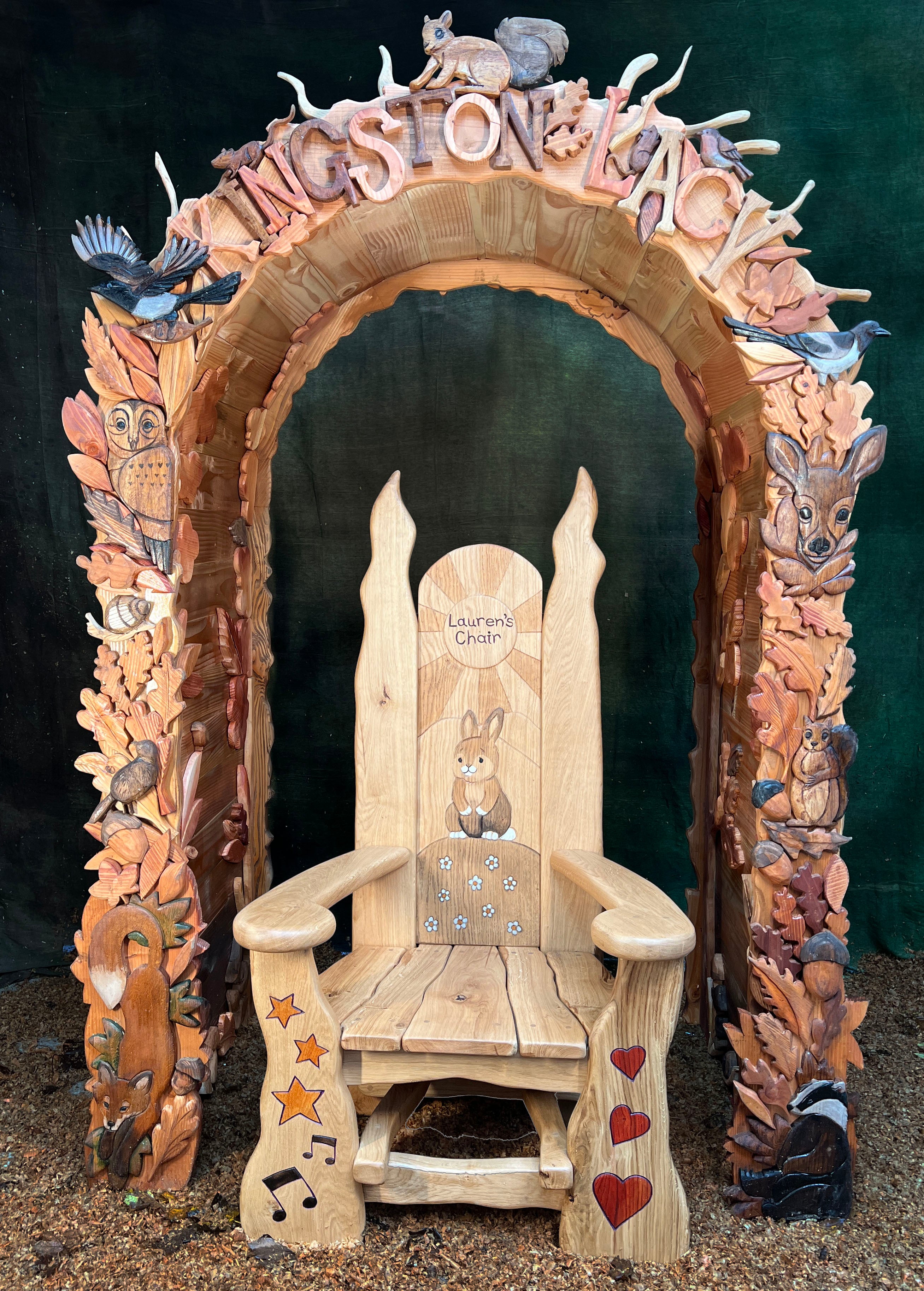 Wooden chair with animal carvings and a decorative archway on a dark background