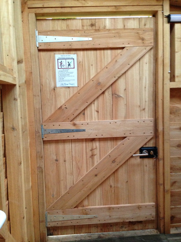 Wooden door of compost toilet with instructional sign