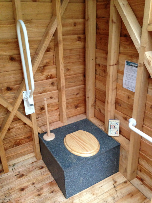 Interior of compost toilet with wooden walls and seat