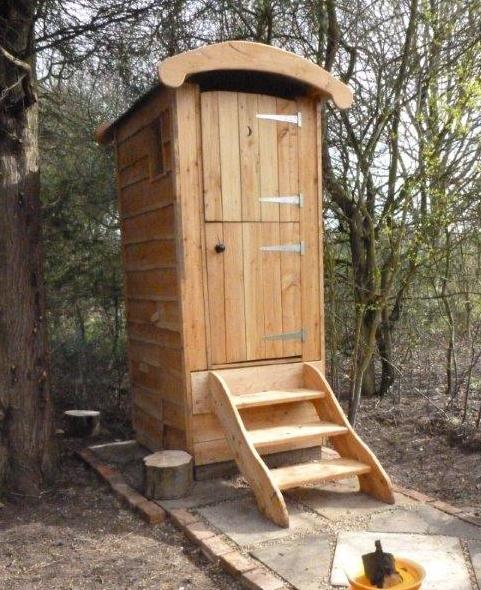 Tall wooden composting toilet in a wooded setting