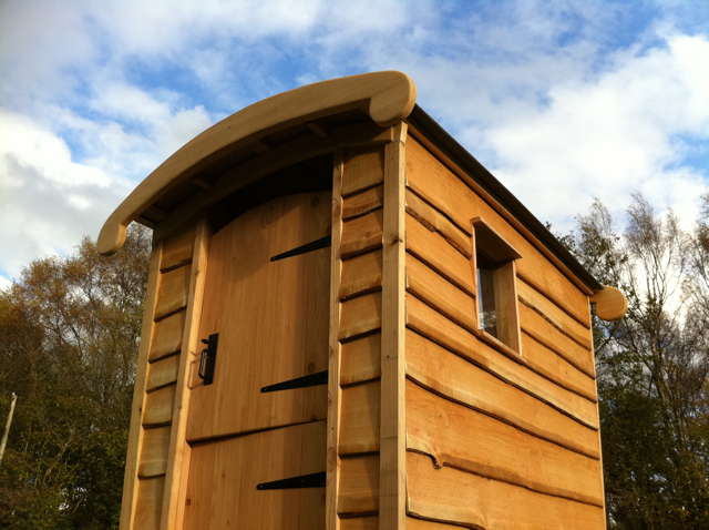 Close-up of wooden compost toilet with curved roof