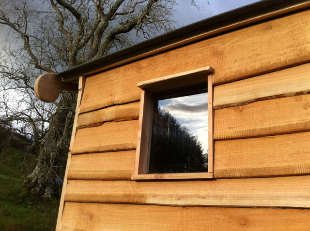 Seitenansicht einer Komposttoilette aus Holz mit Fenster