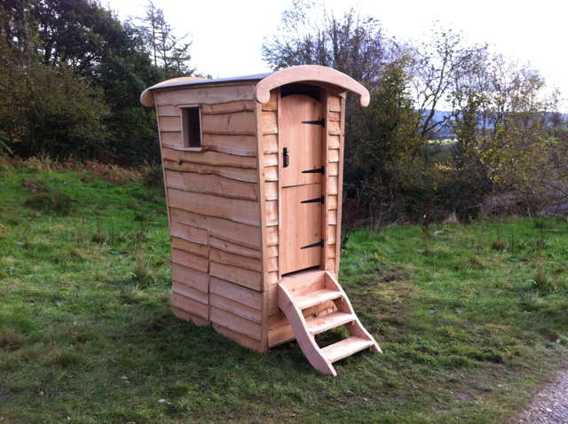 Wooden compost toilet with steps in field