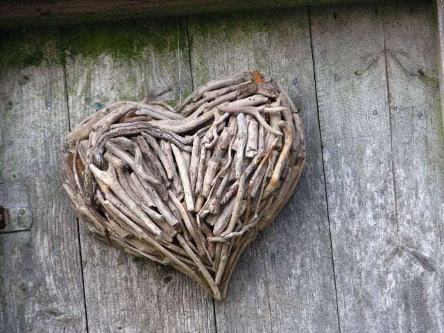 Driftwood heart sculpture on rustic wooden background