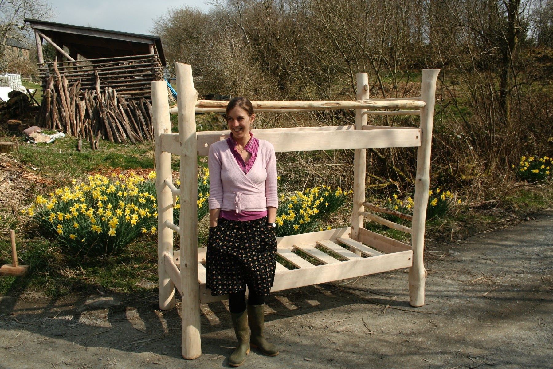 Woman standing beside driftwood bunk bed outdoors