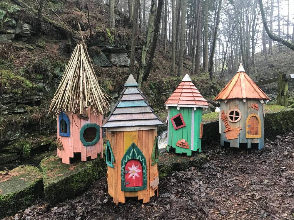 Four colorful fairy houses in a forest setting