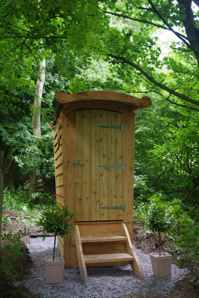 Hölzerne Komposttoilette im üppigen Wald