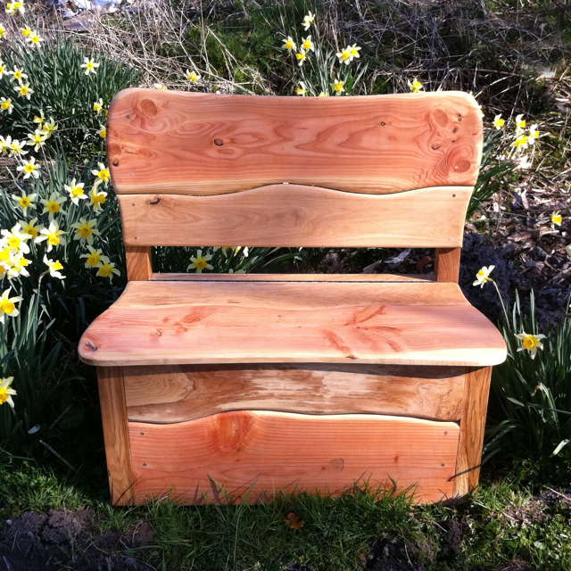 Hand-carved wooden garden storage bench with daffodils