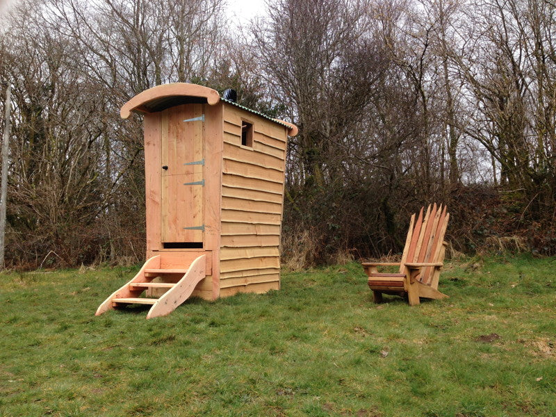 Compost toilet with wooden chair in field