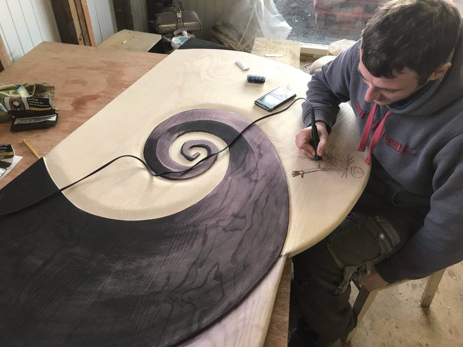 Artisan crafting a spiral design on wood