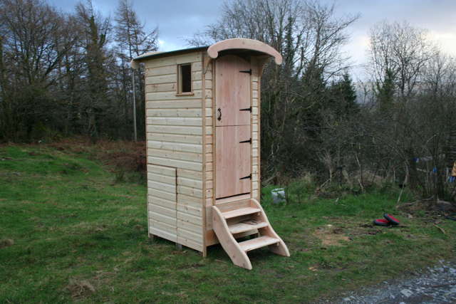 Wooden composting toilet on grassy roadside