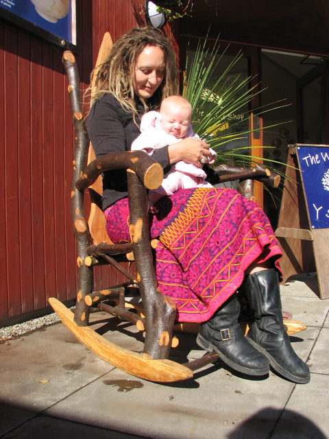 Person sitting on rustic wooden rocking chair outdoors