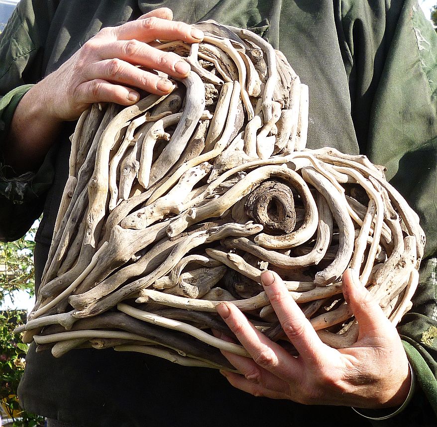 Hands holding small driftwood heart sculpture