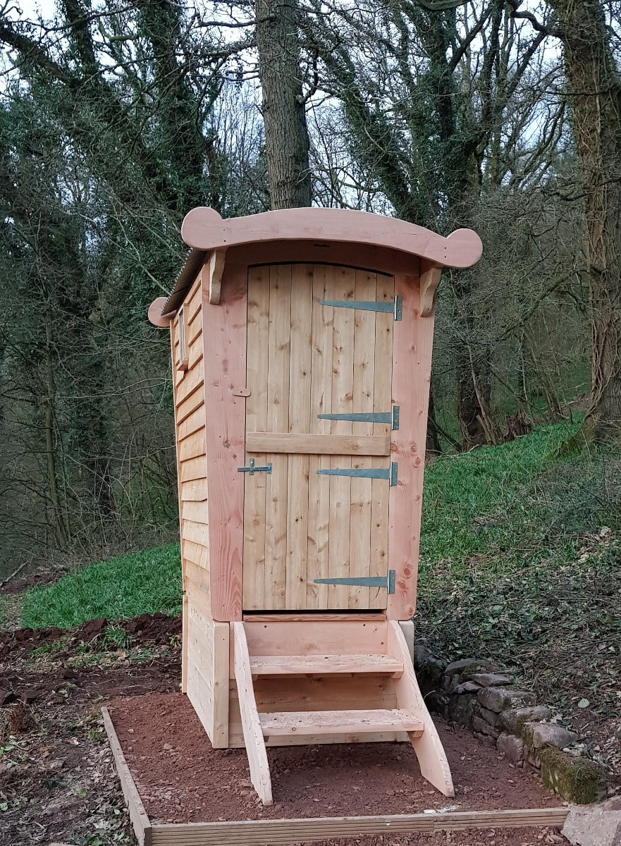 Rückansicht einer Holzkomposttoilette im Wald